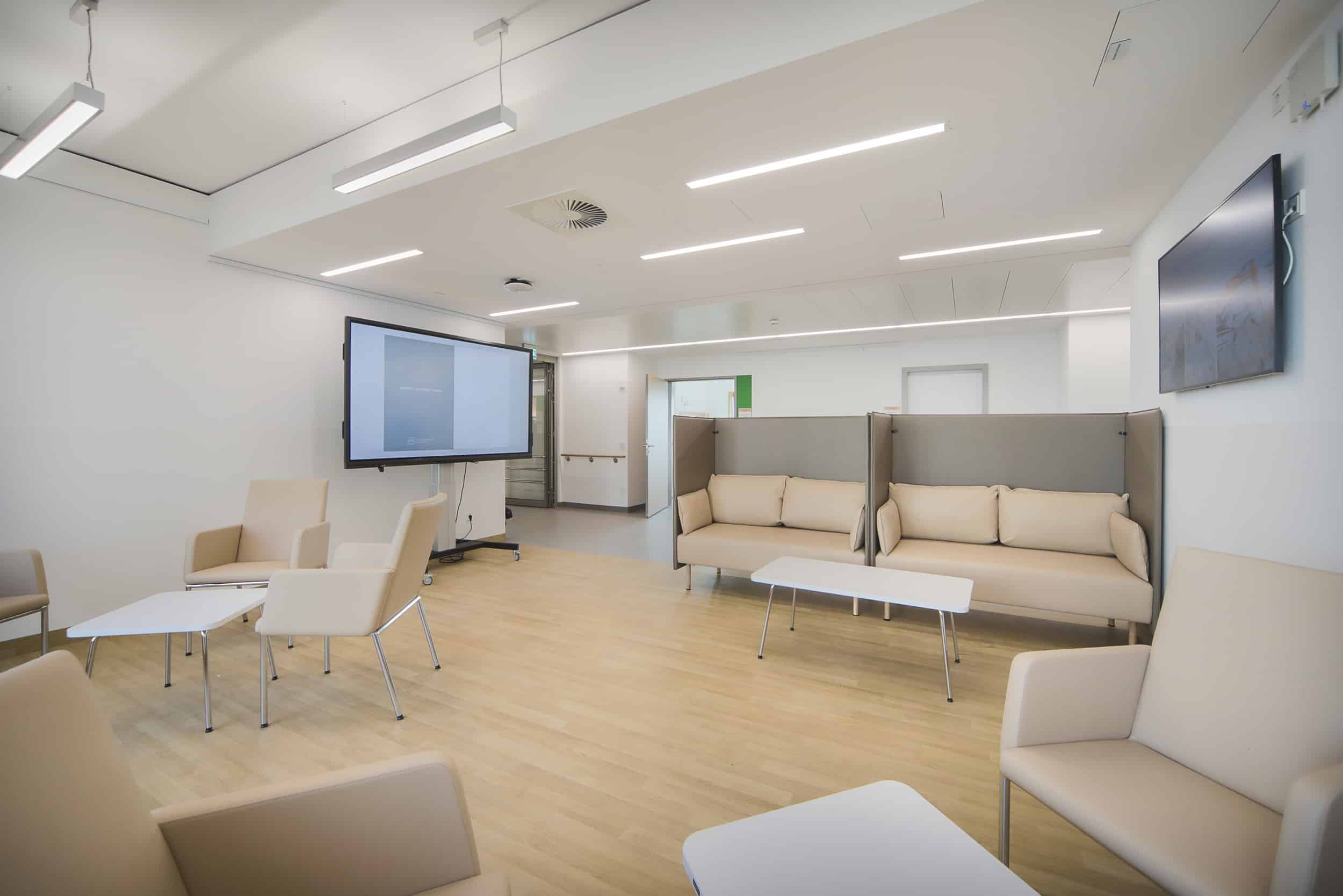 Moderne, minimalistische Wartezimmer-Lounge mit Sofas und Monitor.
