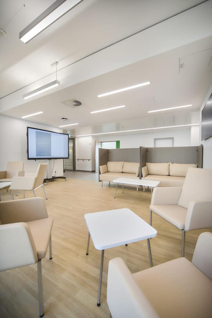 Moderner Warteraum mit beigen Sofas und Tisch.