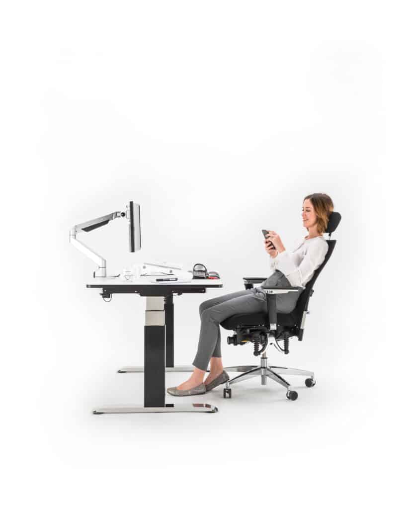 Frau am Schreibtisch, schaut aufs Handy.